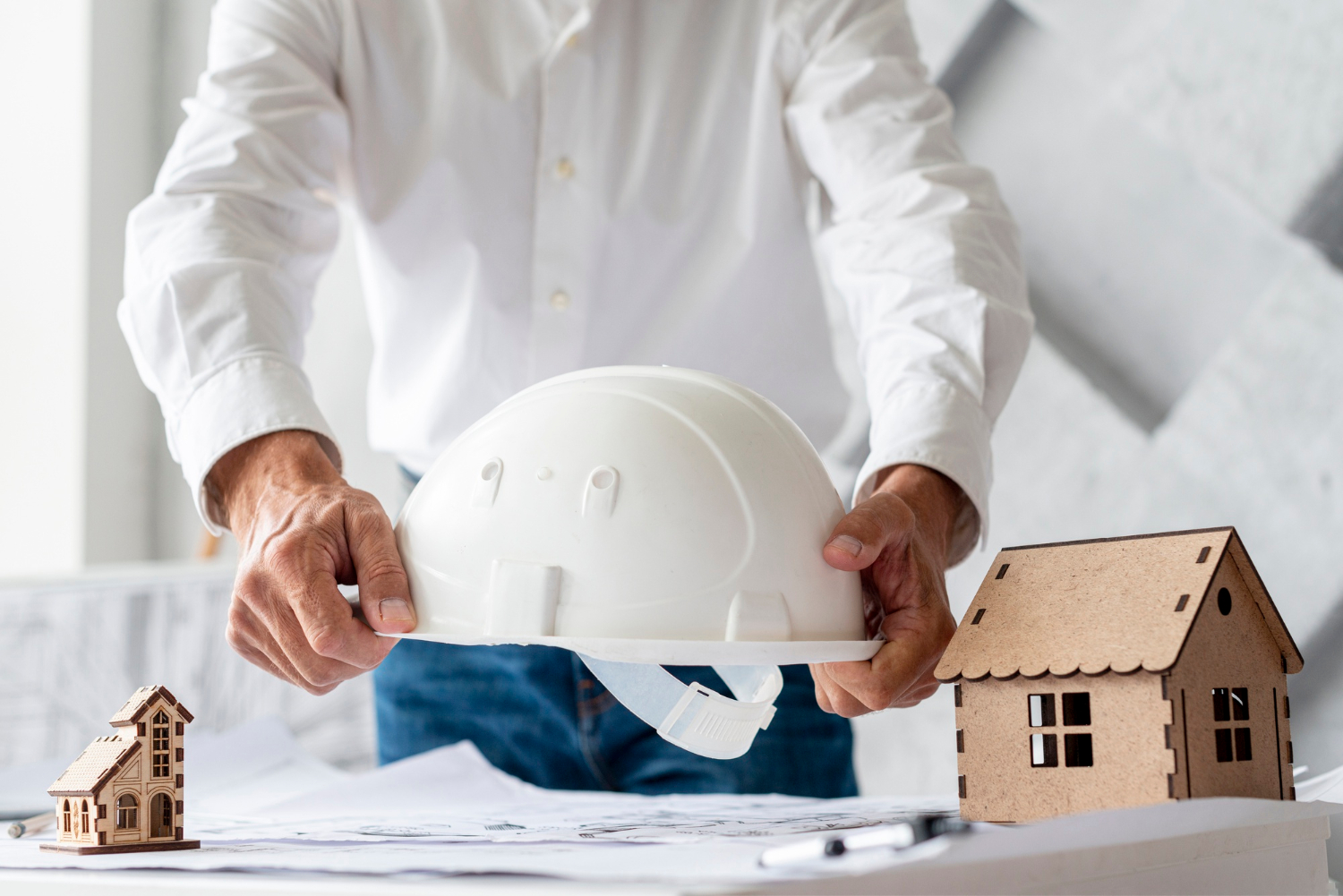 Homme tenant un casque de sécurité au dessus d'un projet de construction de maison